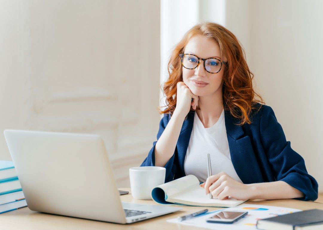 woman looking into camera in front of laptop and no text