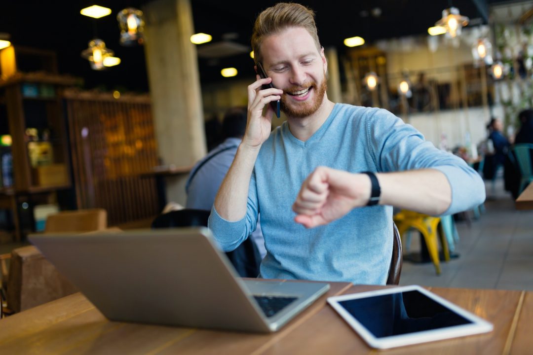 man talking on phone and looking at watch